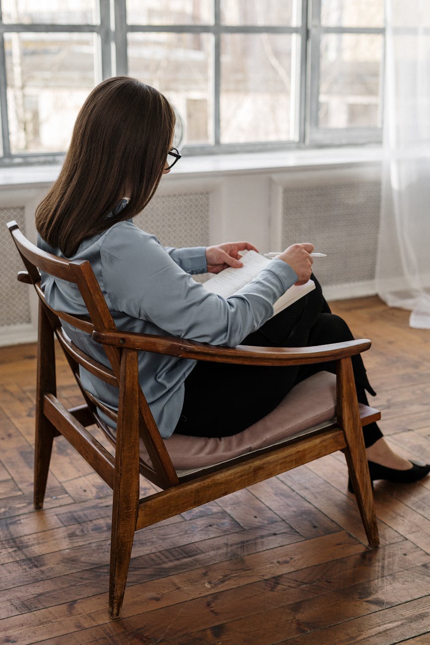 woman in white long sleeve shirt sitting on brown wooden chair