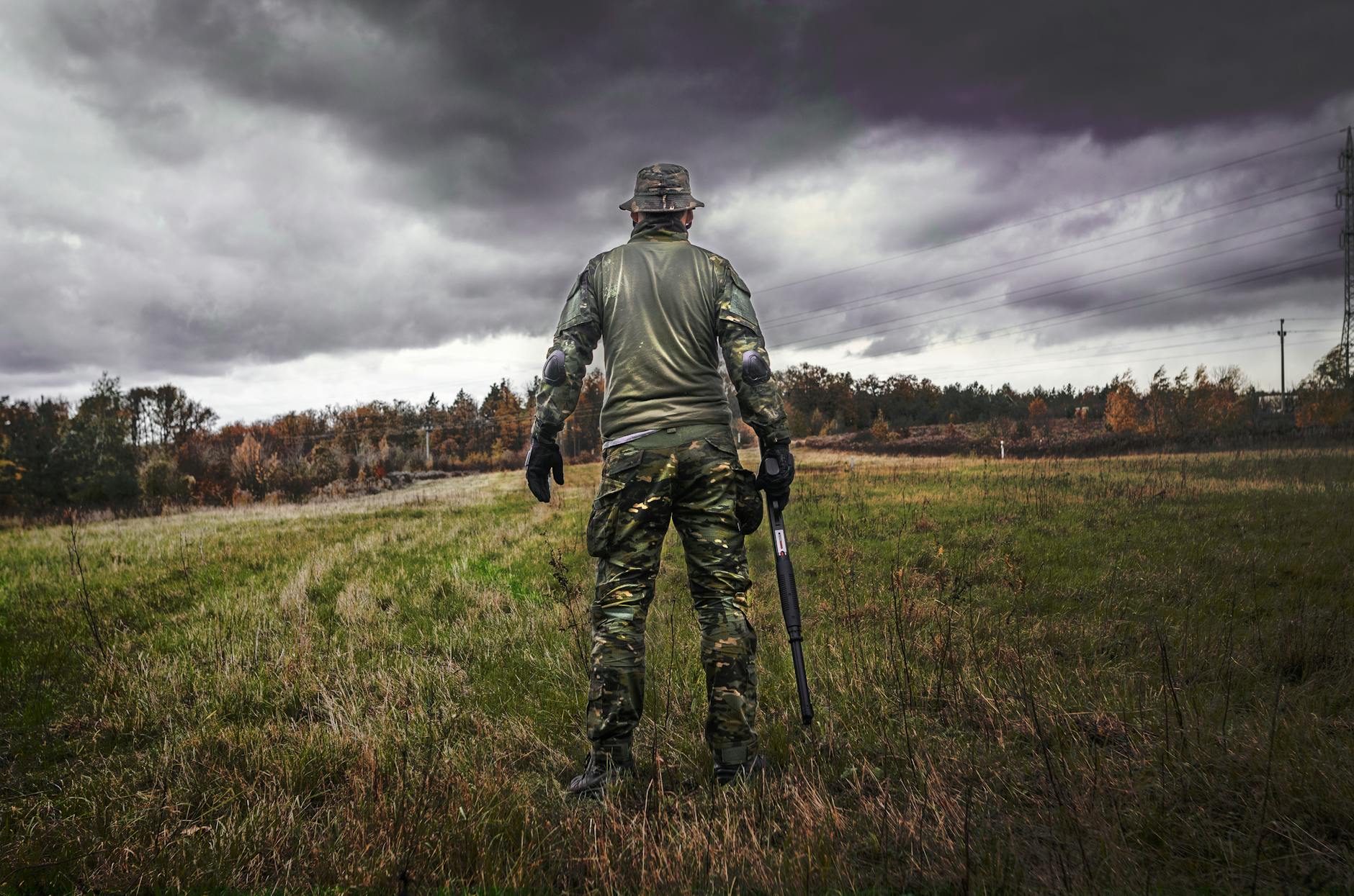 man in camouflage suit holding shotgun